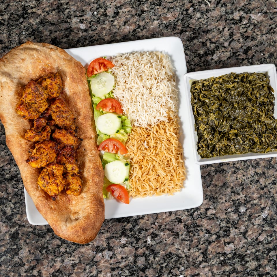 Chicken tikka on naan bread, with rice, salad, and a side of cooked spinach.