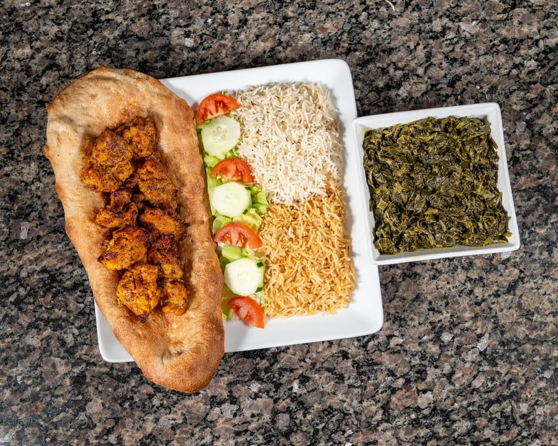Chicken tikka on naan bread, with rice, salad, and a side of cooked spinach.